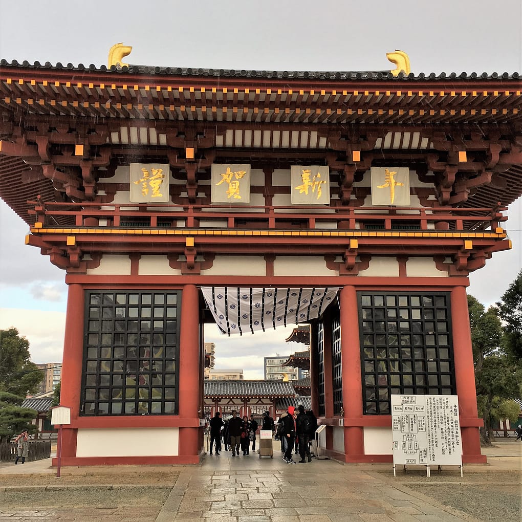 One of the entrance gates to Shitennoji temple. The gate is primarily red and gold, with lattice covering the pillars on either side.