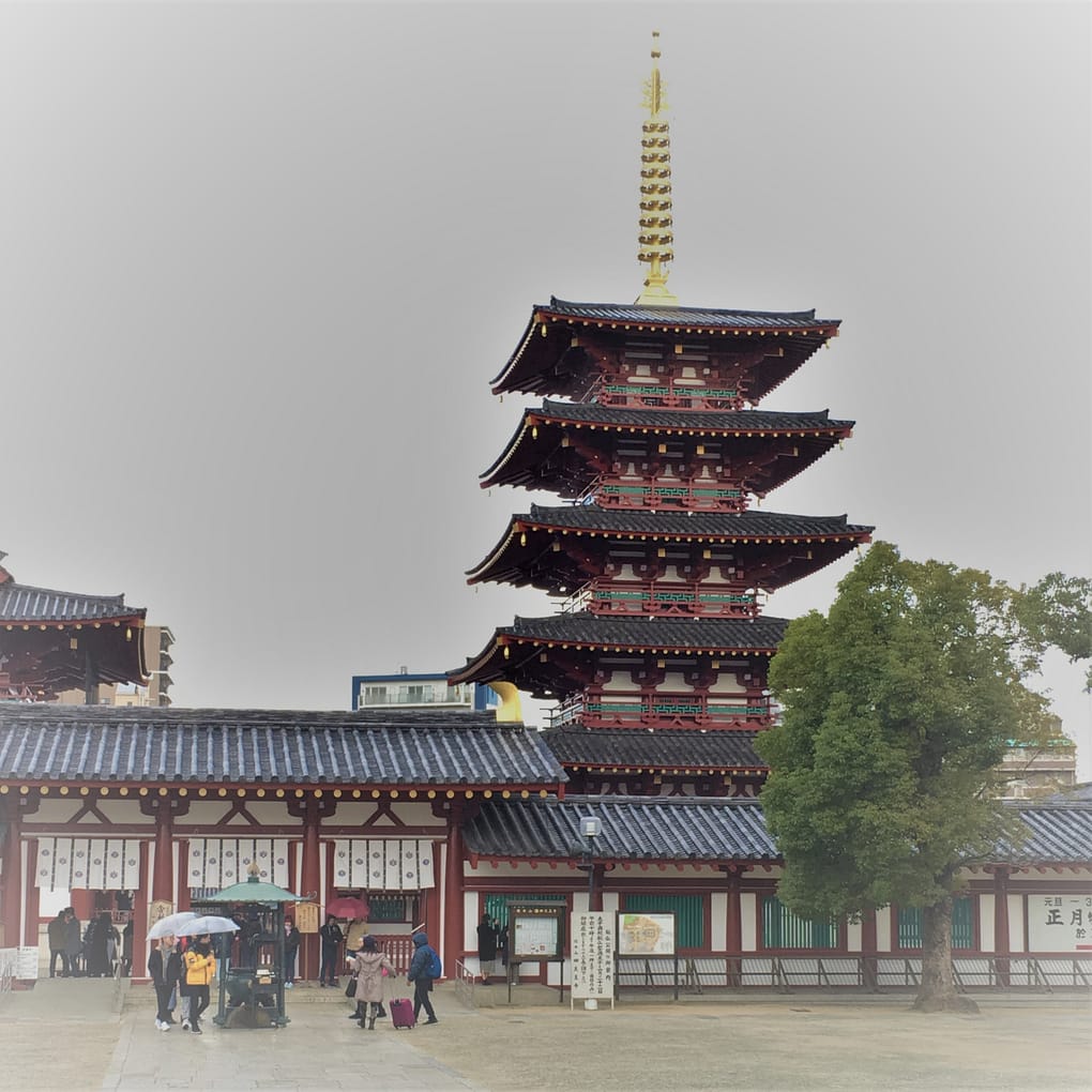 The five story pagoda at Shitennoji temple. There is a gold spire at the top of the structure. A shorter, longer lecture hall is to the left