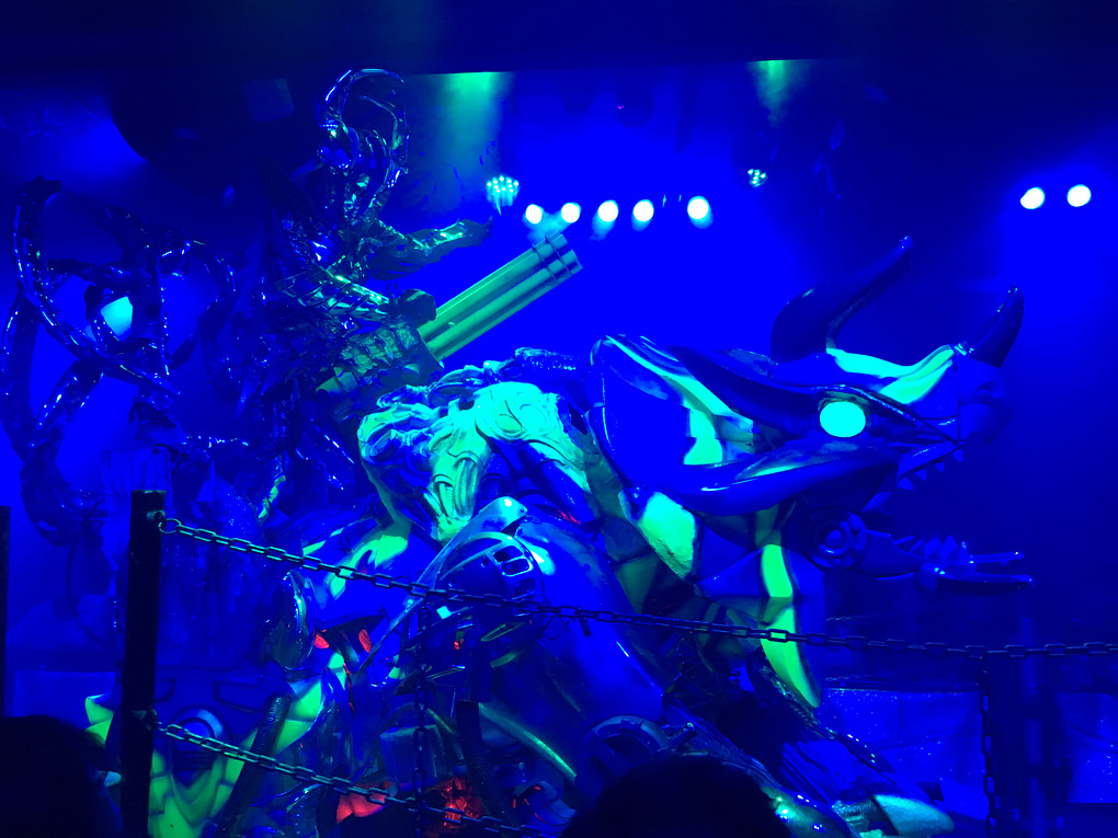 A robot triceratops with neon accents comes from the left. A robot rider is on top