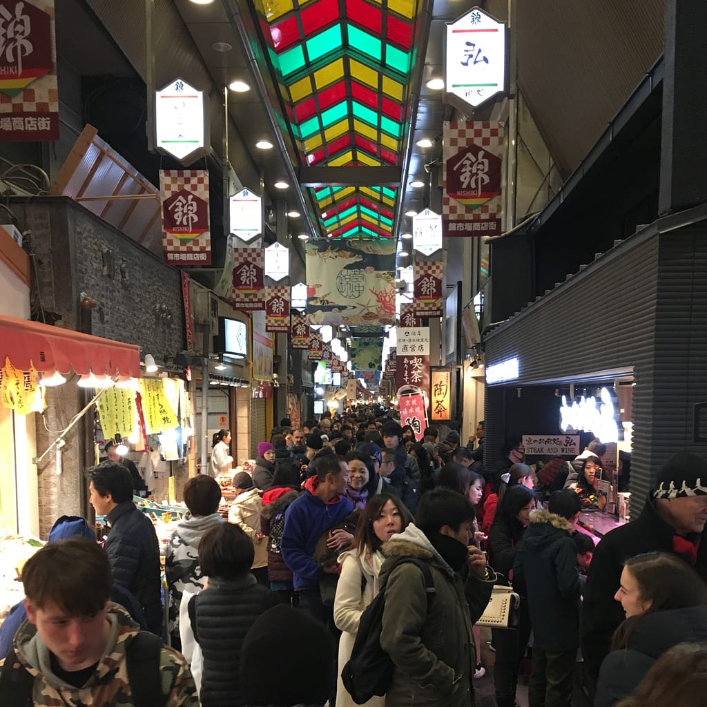 A view down Nishiki market. Stalls are on either side of the crowd that goes all the way down the center of the photo
