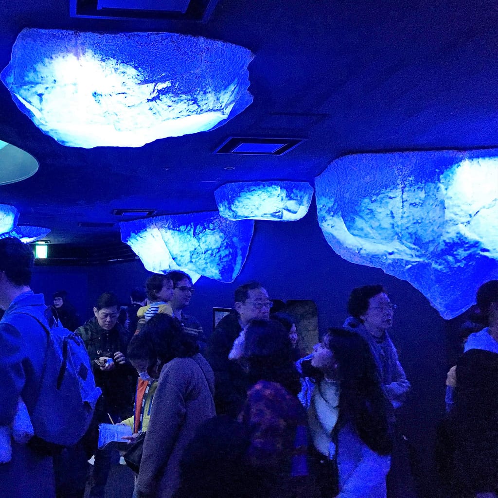 A special exhibit at Kaiyukan Aquarium about marine animals in polar regions. Visitors walk in a dark area with bright ice caps hanging from the ceiling