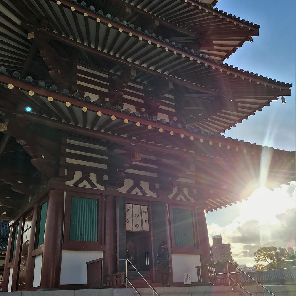An artistic shot of the pagoda at Shitennoji. Only three of the five tiers are in the frame, and the sun is on the lower right side of the frame.