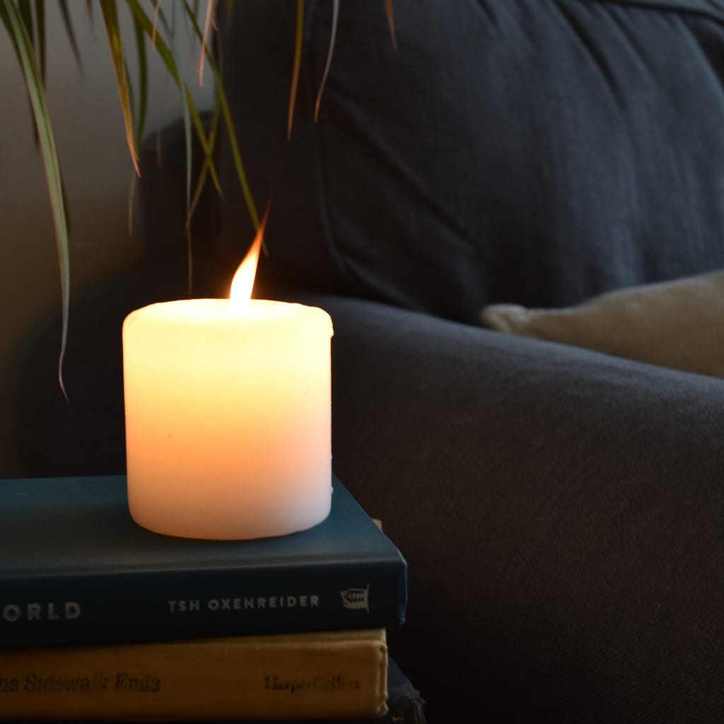 What I Learned Winter - lit candle in front of a blue gray couch