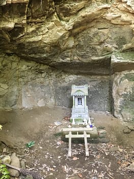 A small shrine and torii gate tucked under an overhanging rock.