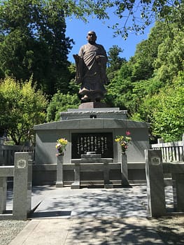 A statue of a bald priest is elevated above a small alter