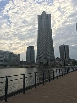 A large tower framed in the later afternoon clouds by the water