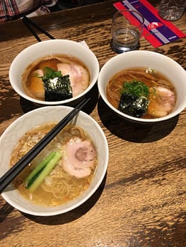Three bowls of ramen together on a wooden table