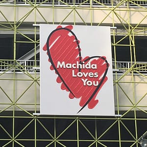 A public sign with a lopsided, hand drawn heart that reads "Machida Loves You"