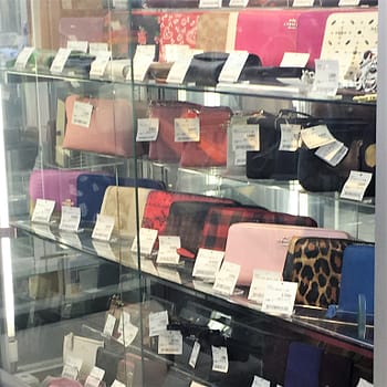 A selection of designer wallets for sale behind glass at the Book Off Super Bazaar thrift store