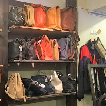 Rows of handbags are lined up on shelves at the thrift store Desert Snow
