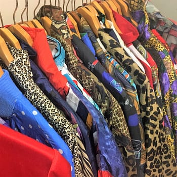 Funky, brightly colored and patterned jackets hang on a clothing rack outside the thrift store Desert Snow