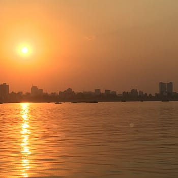 A sunset over the Mekong river with the city skyline silhouetted in the background