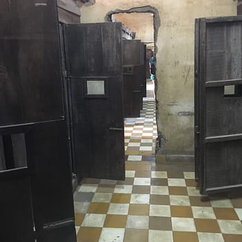 The wooden cell doors of Tuol Sleng swung open