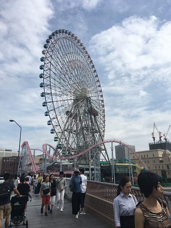 The ferris wheel in Yokohama in front of blue skies and surrounded by people
