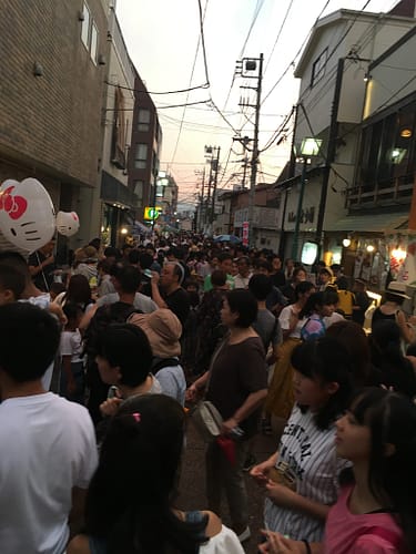 Image shows a narrow street crowded with festival attendees.