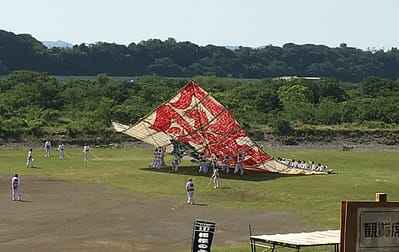 Image shows people running underneath the large kite trying to push it into the air