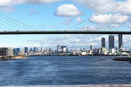 A view of the Osaka skyline from the Osaka bay. City buildings are in the background with water in the foreground.
