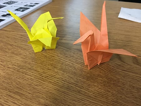 Two folded paper cranes on a table