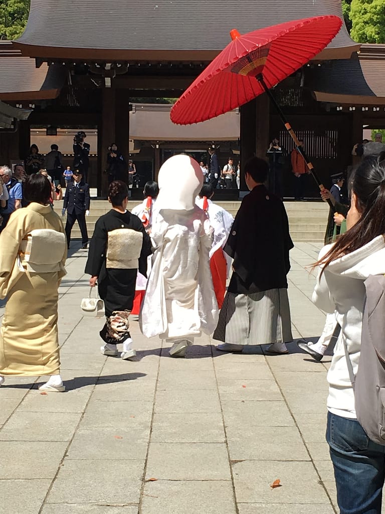 A bride and groom process with attendants toward a wooden gate