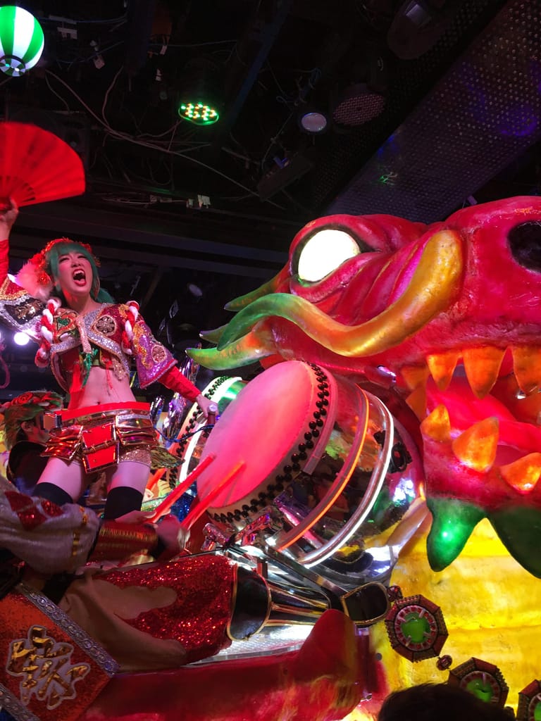 A Japanese performer rides a top a neon dragon
