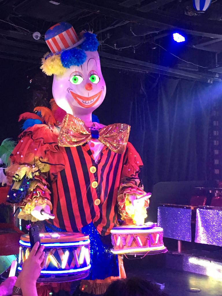 A large animatronic clown playing drums