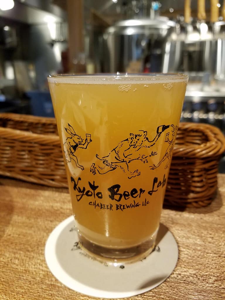 A small glass filled with a orange/yellow IPA beer