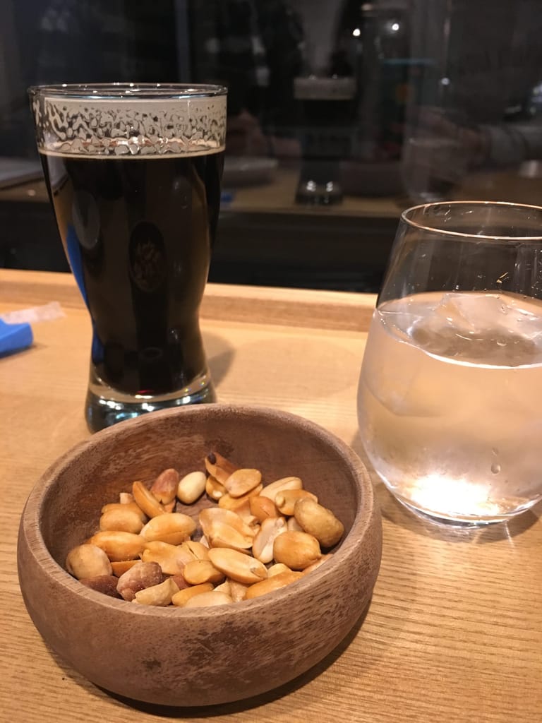 A dark stout beer and a bowl of nuts