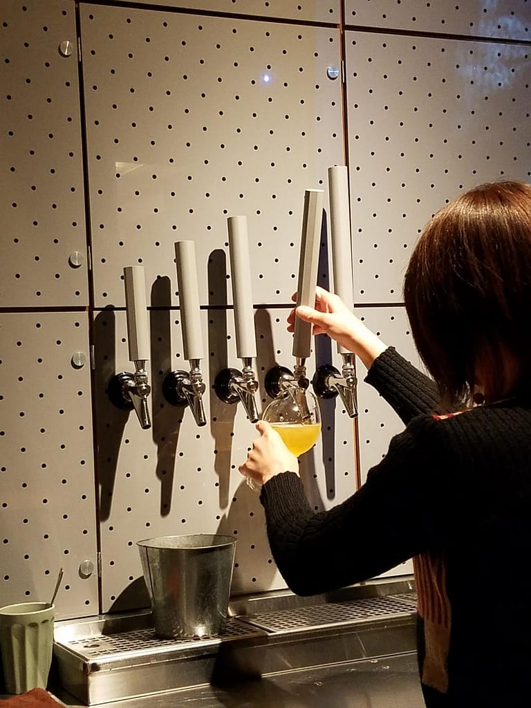 A bartender pours an IPA from taps with a modern, minimalist design